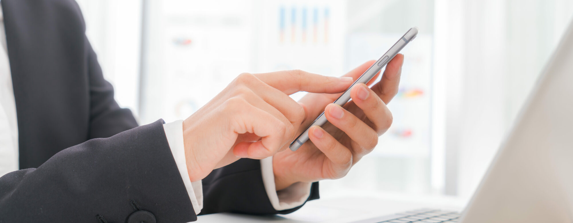 Closeup of business woman hand typing on laptop keyboard with  mobile phone